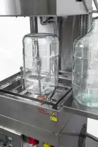 Glass carboy placed upside down on a spray nozzle in an AquaTech BM washer