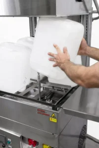 Operator loading plastic jerrycans onto the nozzles of an AquaTech BM container washer