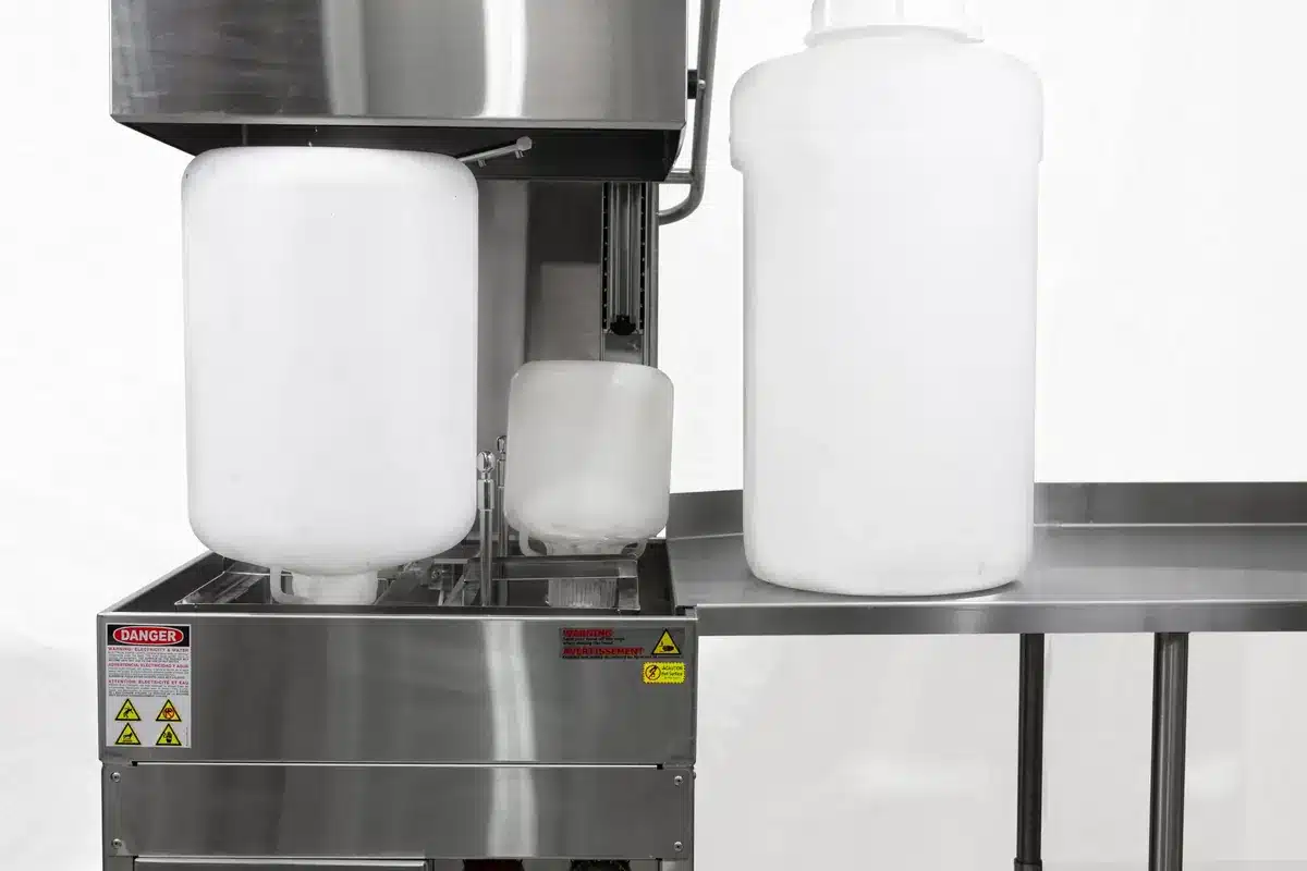 Laveuse de bouteilles MFW XL AquaTech BM chargée de grands bidons, avec sa table de travail latérale en inox