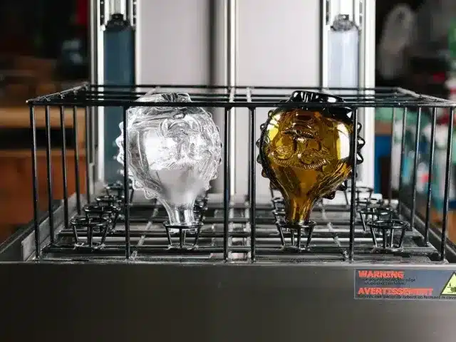 Sculpted spirits bottles neck down in a bottle washer basket